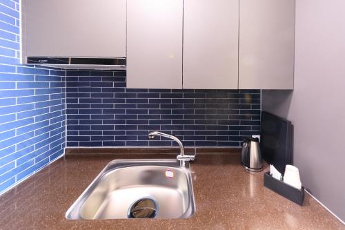 a stainless steel sink in a kitchen with blue tiles at Gaon Resort Byeongsan in Buan