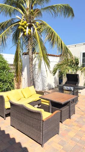 a patio with wicker chairs and tables and a palm tree at Aruba Ariba Exclusive Pool Suites in Saliña Cerca