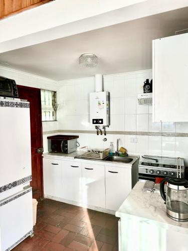 a kitchen with white cabinets and a stove top oven at Espectacular Casa en El Canelo, Algarrobo in Algarrobo