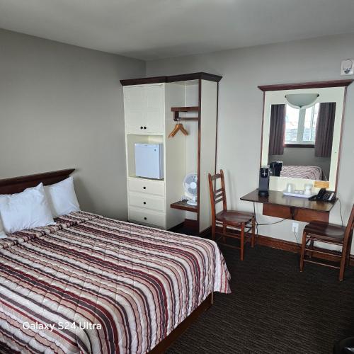 a hotel room with a bed and a desk and a mirror at Auberge Sur Mer Charlevoix in Saint-Siméon