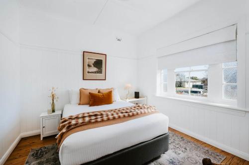 una camera da letto bianca con un letto e una finestra di Mygoura Cottage - Charming Country Living in Town a Mudgee