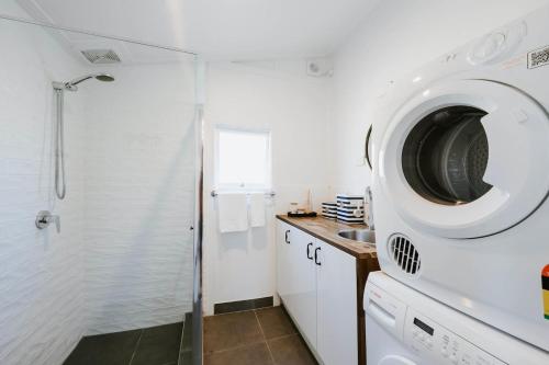 un bagno con doccia e lavatrice di Mygoura Cottage - Charming Country Living in Town a Mudgee