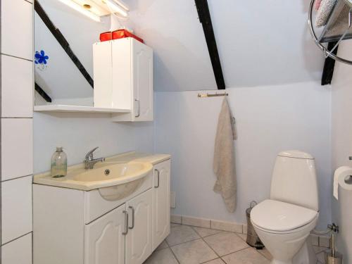 a white bathroom with a toilet and a sink at Tranquil Thatched Cottage on Romo-By Traum in Toftum