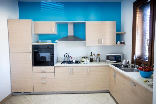 a kitchen with wooden cabinets and a blue wall at Holiday Home Nicola Santoro in Custonaci