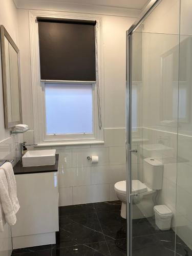 a bathroom with a toilet and a glass shower at ARK Apartments in Echuca