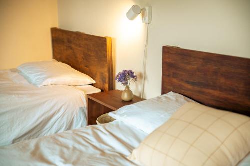 a bedroom with two beds and a table with a vase of flowers at Casa del Sol Antigua in Antigua Guatemala