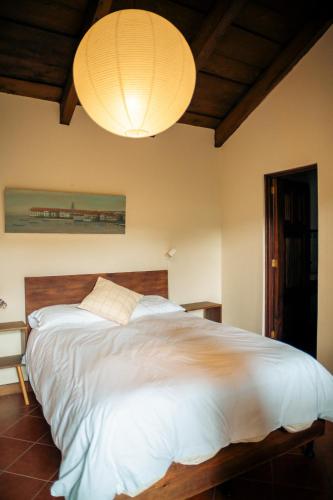 a bedroom with a large white bed and a chandelier at Casa del Sol Antigua in Antigua Guatemala