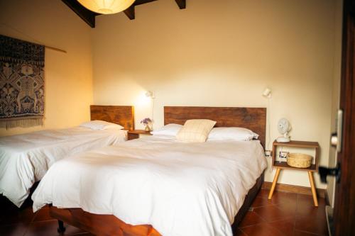 two beds in a room with white sheets at Casa del Sol Antigua in Antigua Guatemala