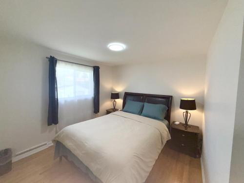 a bedroom with a bed and two lamps and a window at Warm Welcome Home in Longueuil