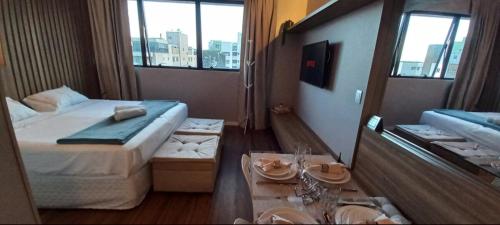 una camera d'albergo con letto e tavolo con piatti di Flat Região Nobre a Curitiba