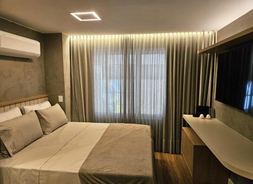 a bedroom with a bed and a large window at Loft Búzios - CLN 202 in Brasilia