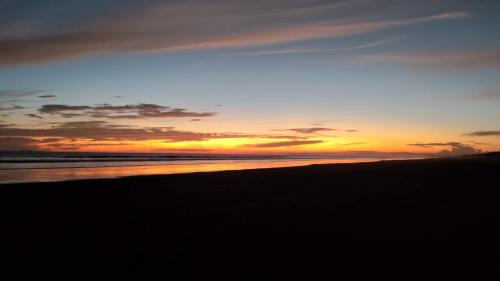 a sunset on a beach with the ocean at Mike's Adventures Guest House in David