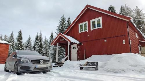 a car parked in front of a red building in the snow at Landgård Feriehus in Trysil