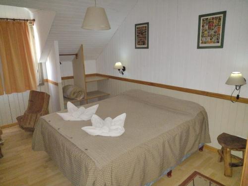 a bedroom with a bed with two white towels at Hosteria y Restaurante Hua Hum in San Martín de los Andes