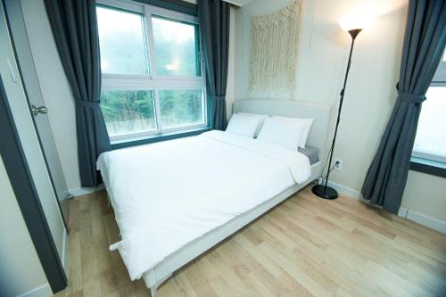 a white bed in a room with a window at Yangyang Ocean Hill in Yangyang