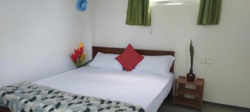 a bedroom with a white bed with a red pillow at Sun Beach Villa in Weligama