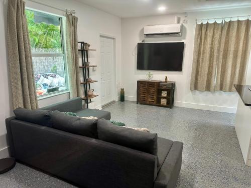 a living room with a couch and a flat screen tv at Flora's Garden Apartment/Studio in North Miami