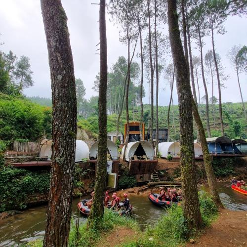 a group of people rafting down a river with tents at Tepian Pinus Glamping in Palayangan