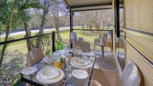 a table with plates and glasses on a balcony at Anchorage Holiday Park in Iluka