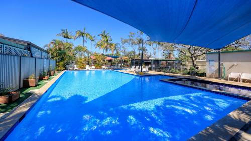 a large blue swimming pool with a blue umbrella at Anchorage Holiday Park in Iluka