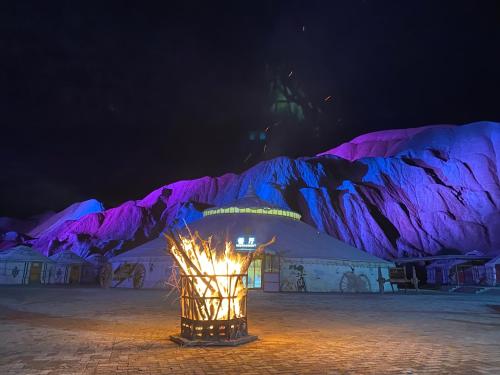 a lit up tent with a mountain in the background at KaoShan Tent Zhangye in Zhangye