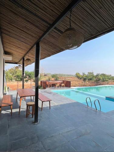 a patio with a table and chairs next to a pool at Manduva house in Zahirābād