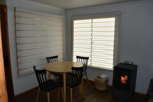 a dining room with a table and chairs and a stove at Cabaña Niebla in Valdivia