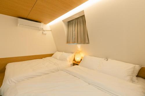 two white beds in a room with a window at Hotel Daun Guri in Guri