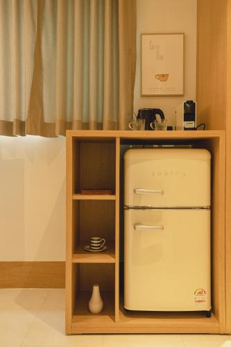 a small kitchen with a refrigerator and a shelf at Hotel Daun Guri in Guri