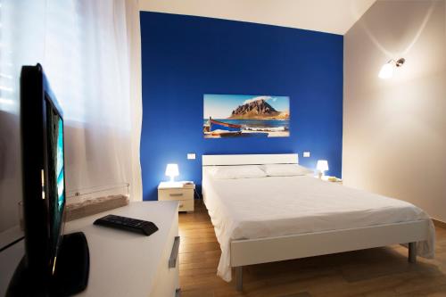 1 dormitorio con 1 cama, TV y pared azul en Holiday Home Nicola Santoro, en Custonaci