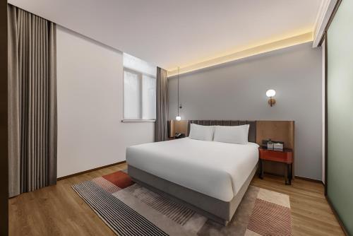 a bedroom with a white bed and a window at 上海浦东机场华美达安可酒店-免费提供24小时浦东机场班车十分钟到达候机楼出发层 in Shanghai