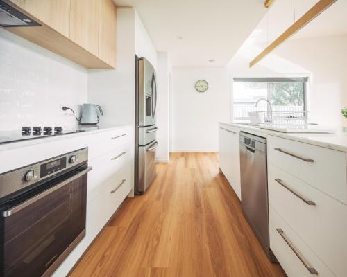 a kitchen with white cabinets and a wooden floor at The Pavilion in Port Sorell