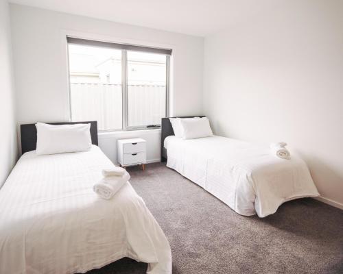 two beds in a room with a window at The Pavilion in Port Sorell
