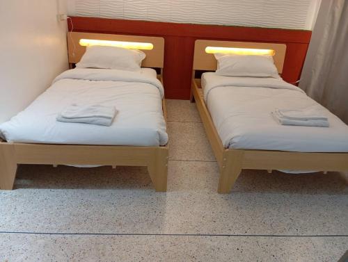two beds in a room with towels on them at สุขสิริ เบตง Suksiri homestay in Betong