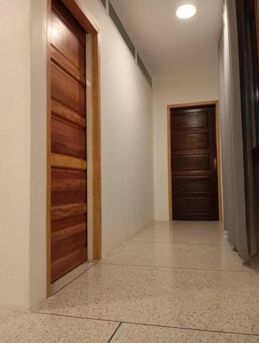 a hallway with two wooden doors and a tile floor at สุขสิริ เบตง Suksiri homestay in Betong
