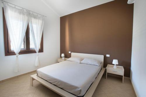 a bedroom with a white bed and two windows at Holiday Home Nicola Santoro in Custonaci