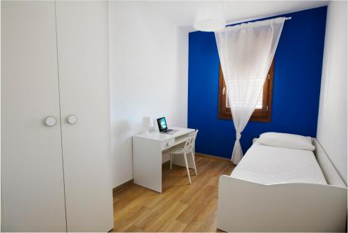 a bedroom with a blue wall and a bed and a desk at Holiday Home Nicola Santoro in Custonaci