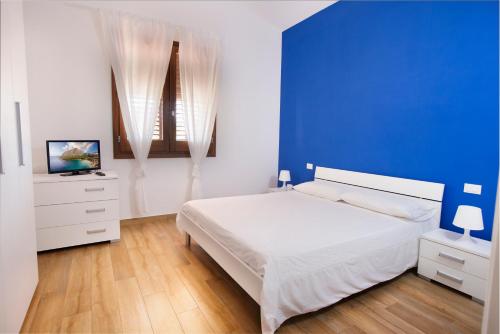 a bedroom with a blue wall and a white bed at Holiday Home Nicola Santoro in Custonaci