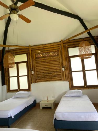 two beds in a room with two windows at El Tesoro - Finca Hotel Eje Cafetero in Calarcá