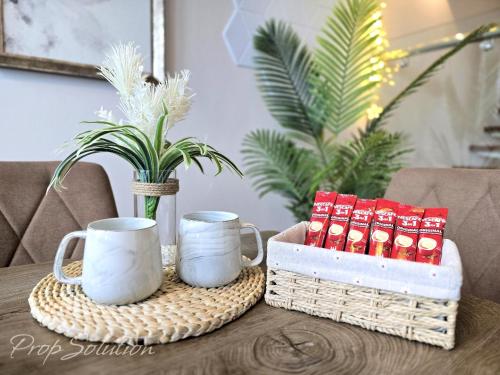 a table with two mugs and a basket on it at Spacious Cozy Elysia Suite Johor Bahru Legoland in Iskandar Puteri