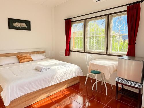a bedroom with a bed and a table and a window at Samui Smile Stay in Mae Nam