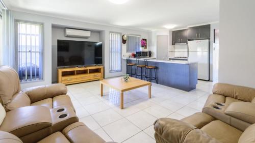 a living room with two couches and a kitchen at The Eel Place Retreat in Bongaree