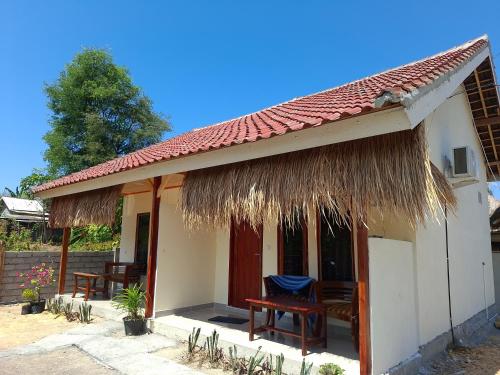 a small house with chairs and a thatched roof at Ekas Elen Homestay in Pulau Gilkaliantan