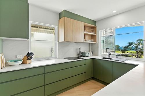 a kitchen with green cabinets and a large window at Unit 2 Beach Gallery in Yaroomba