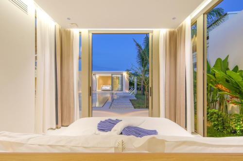 a bed in a room with a large window at Asherah Villa By Asherah Team in Ban Phru Champa