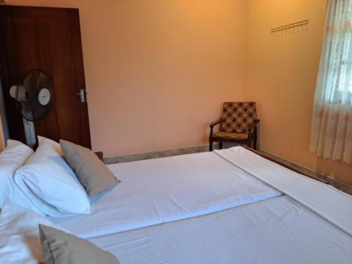a bedroom with a large white bed and a chair at Shady Homestay in Matara