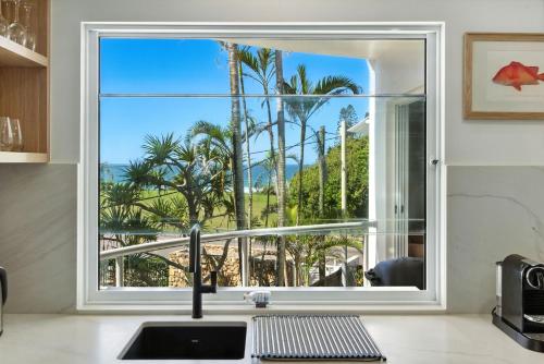 a kitchen window with a view of palm trees at Unit 2 Beach Gallery in Yaroomba