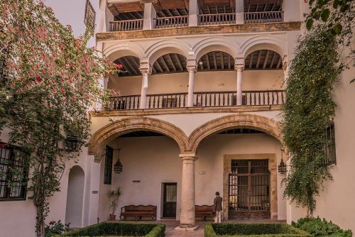 a man standing in front of a building with a balcony at Las Casas de la Judería de Córdoba in Córdoba