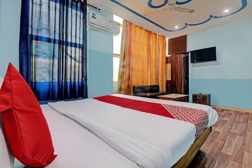 een slaapkamer met een bed met een rood kussen erop bij Hotel O White Swan in Vibhuti Khand