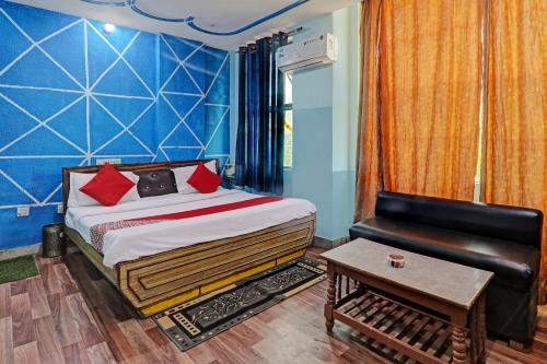 a bedroom with a bed and a couch and a table at Hotel O White Swan in Vibhuti Khand